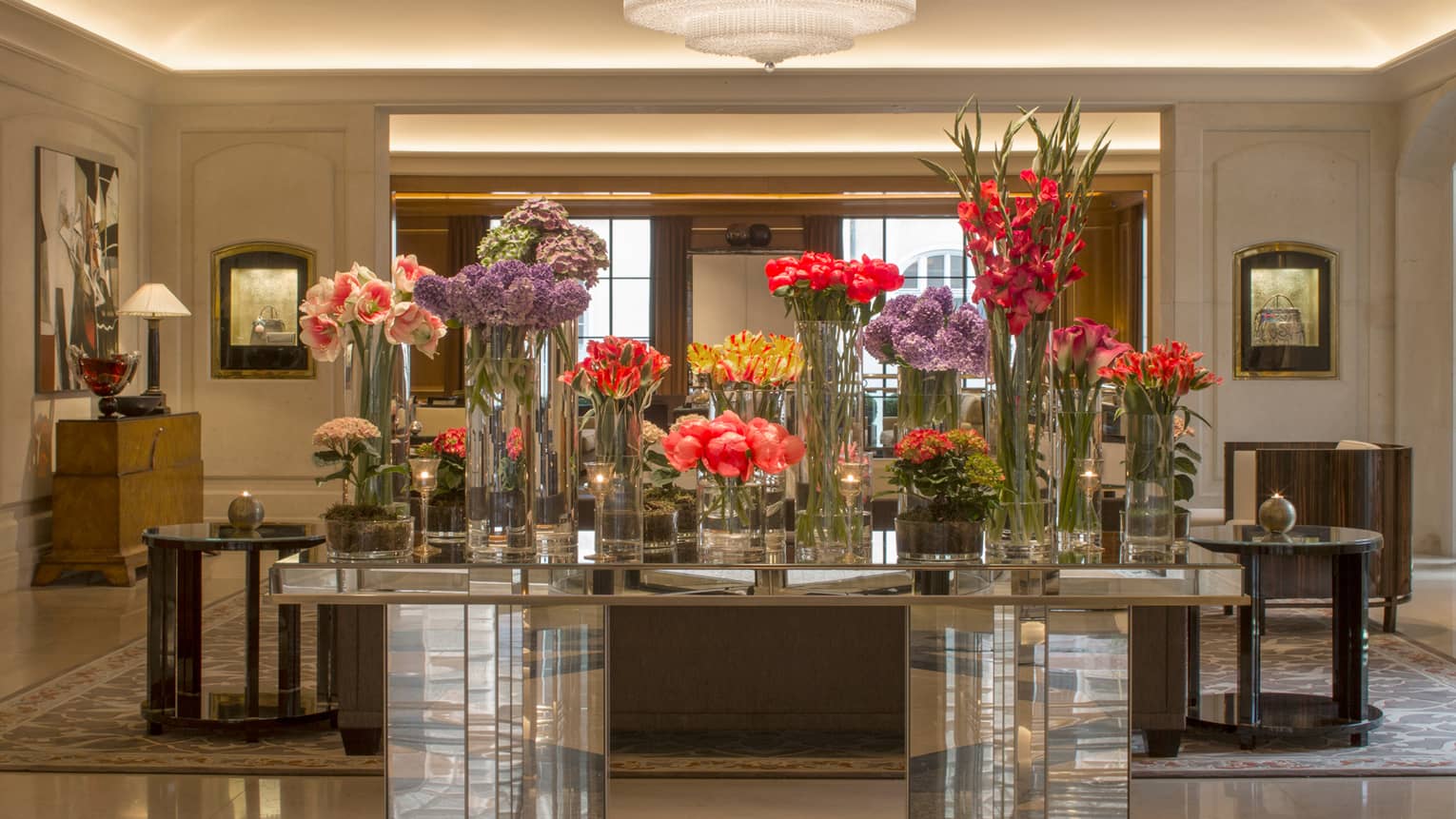 Hotel lobby with multiple crystal vases with flowers of different heights on tabletop