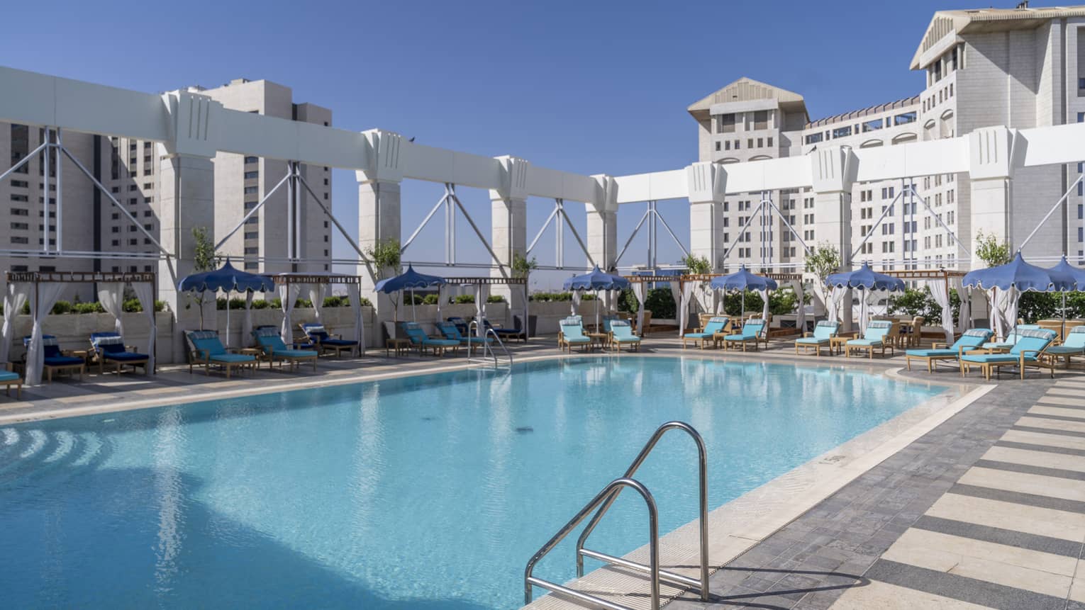 Outdoor pool surrounded by teal lounge chairs and white column