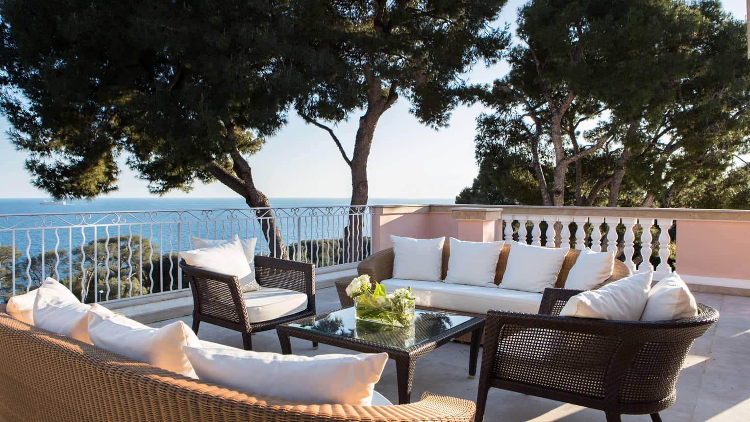 Plush patio sofas, chairs on veranda by trees, Mediterranean Sea views