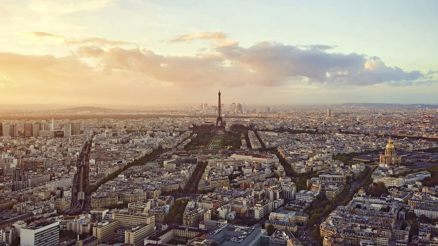 Sweeping city view of Paris rooftops, buildings, Eiffel tower at sunset