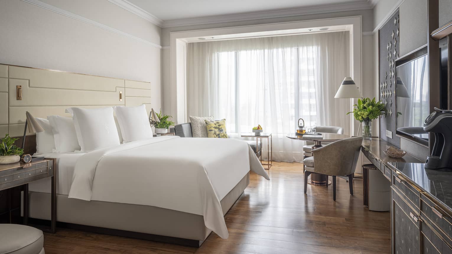 Guest room with a king-sized bed, cosy seating area and large windows offering natural light.