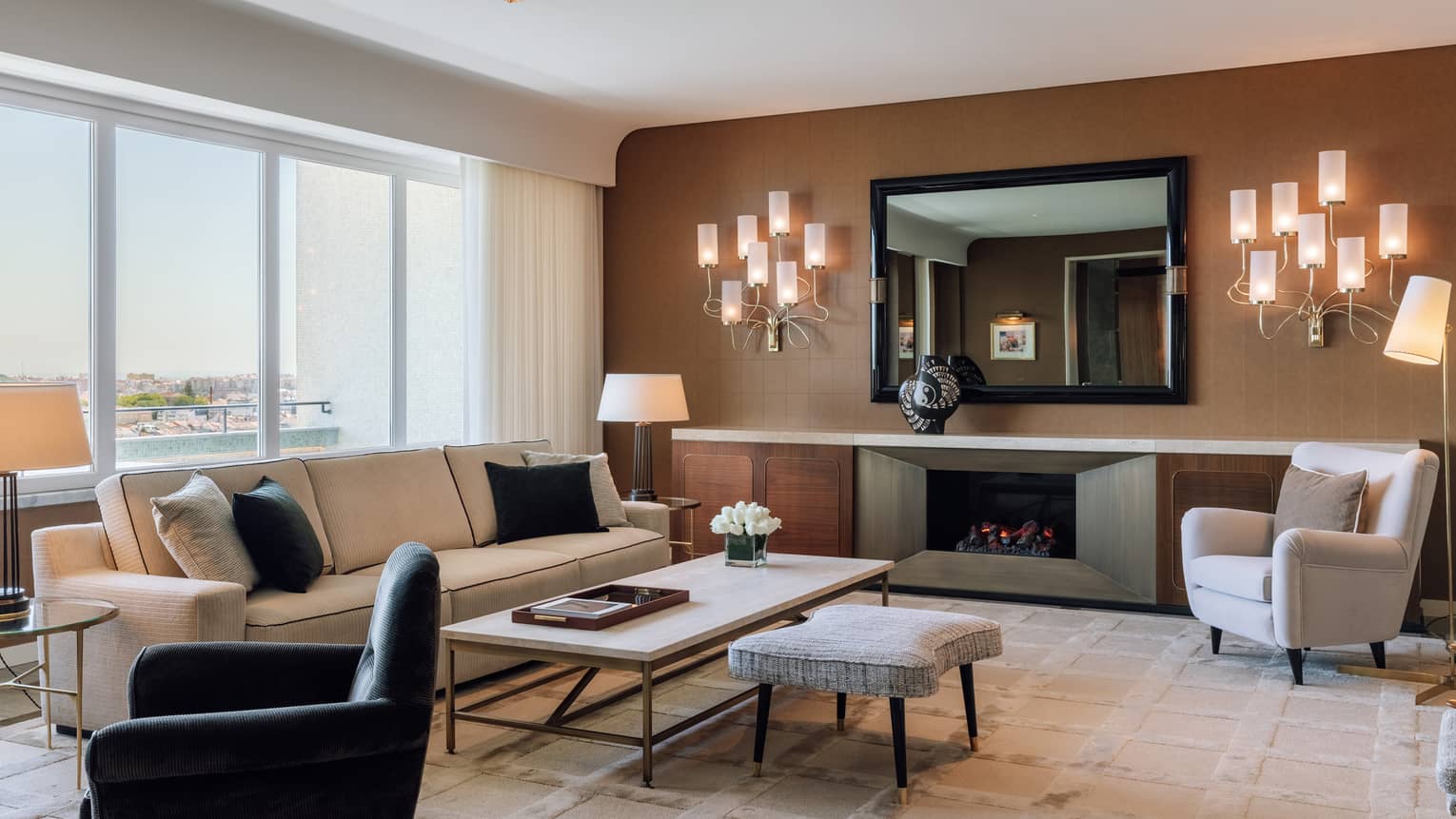Living room with cream sofa, white arm chair, black arm chair, wall schones, brown accent wall