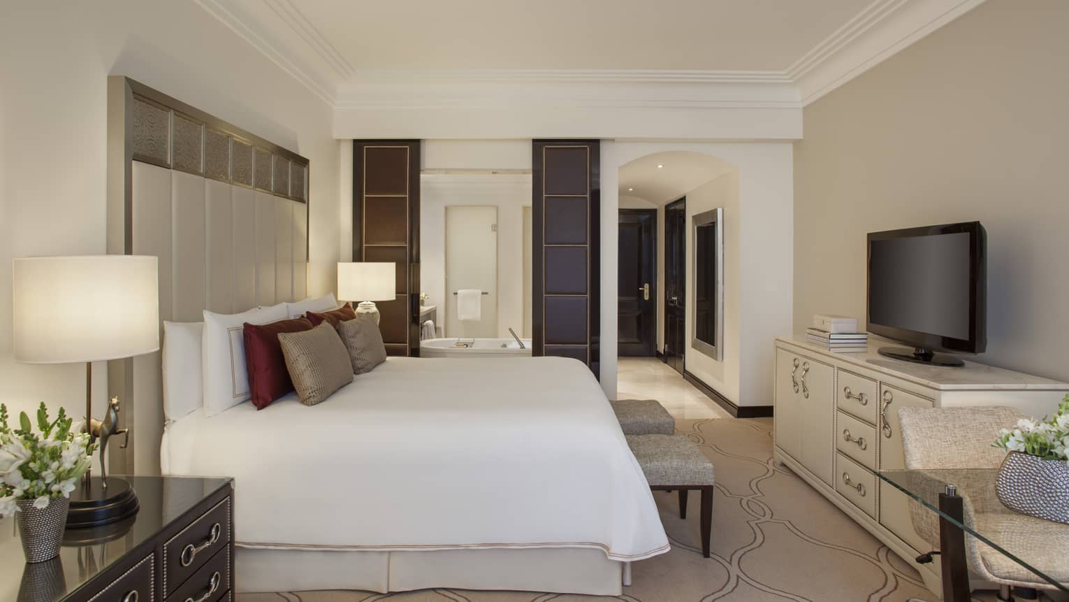 E-Lounge Room modern white decor, bed with tall headboard, burgundy and beige silk pillows, modular shelves