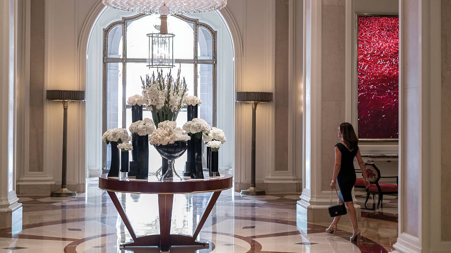 Luxury Hotel Beverly Hills Wilshire A Four Seasons Woman Walks By Round Table With Multiple Vases White Flowers In Marble Hotel Lobby