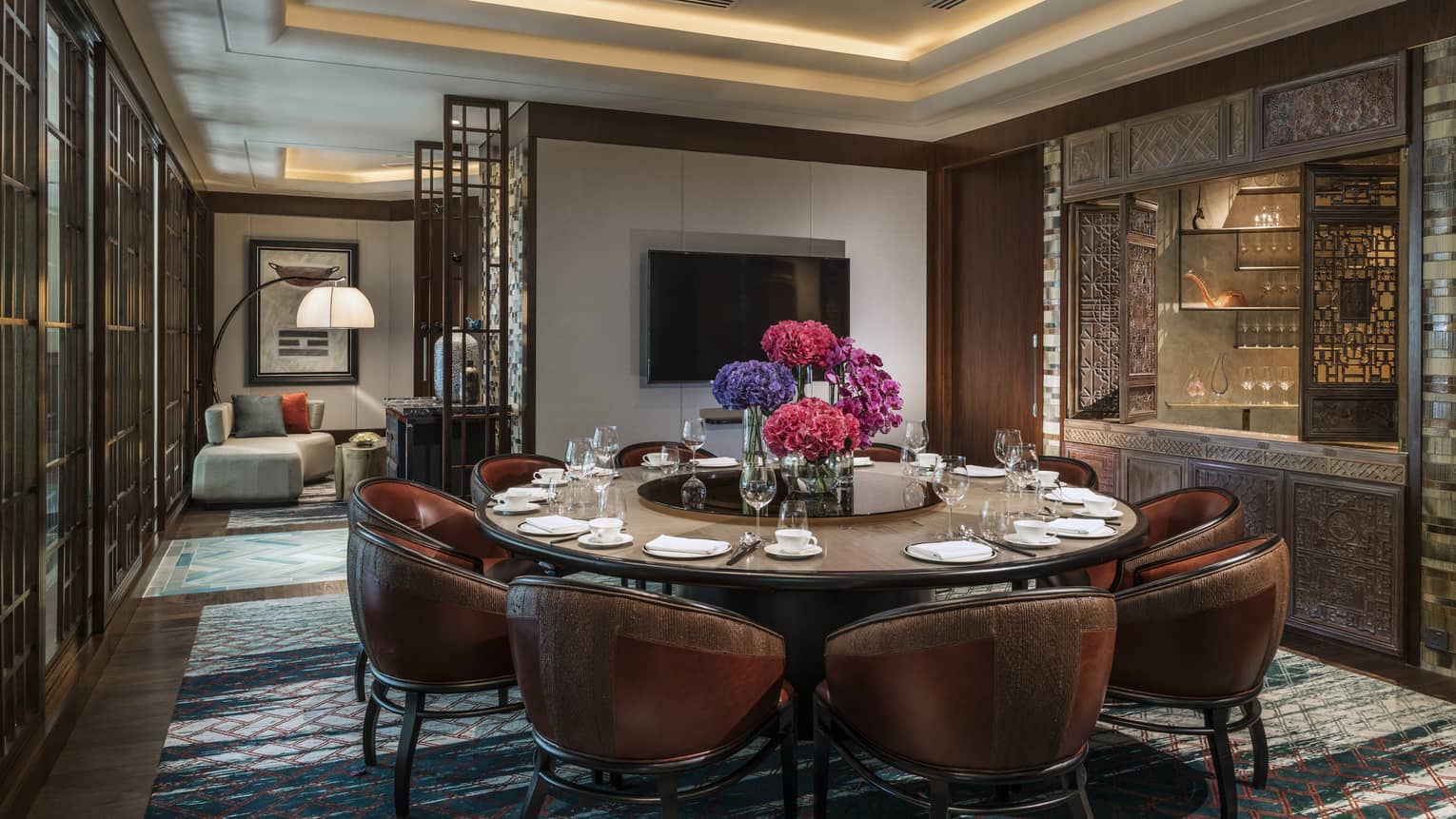 Leather bucket chairs around private meeting dining table, TV on wall