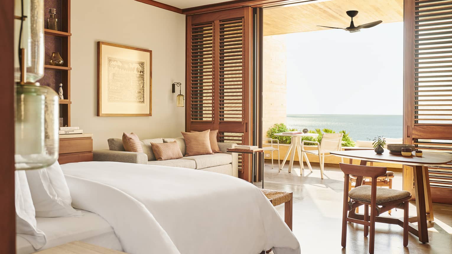 Beach-view hotel room with shutter doors opening to terrace