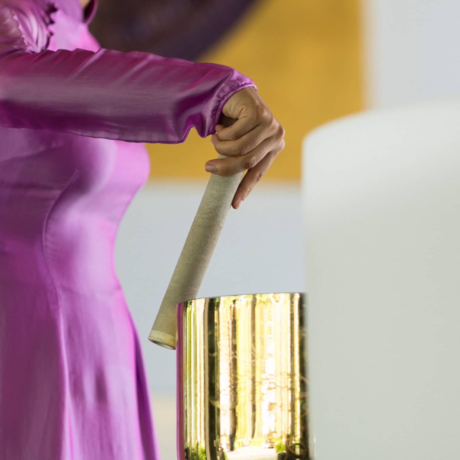 Woman holding stick plays gold quartz-crystal bowl