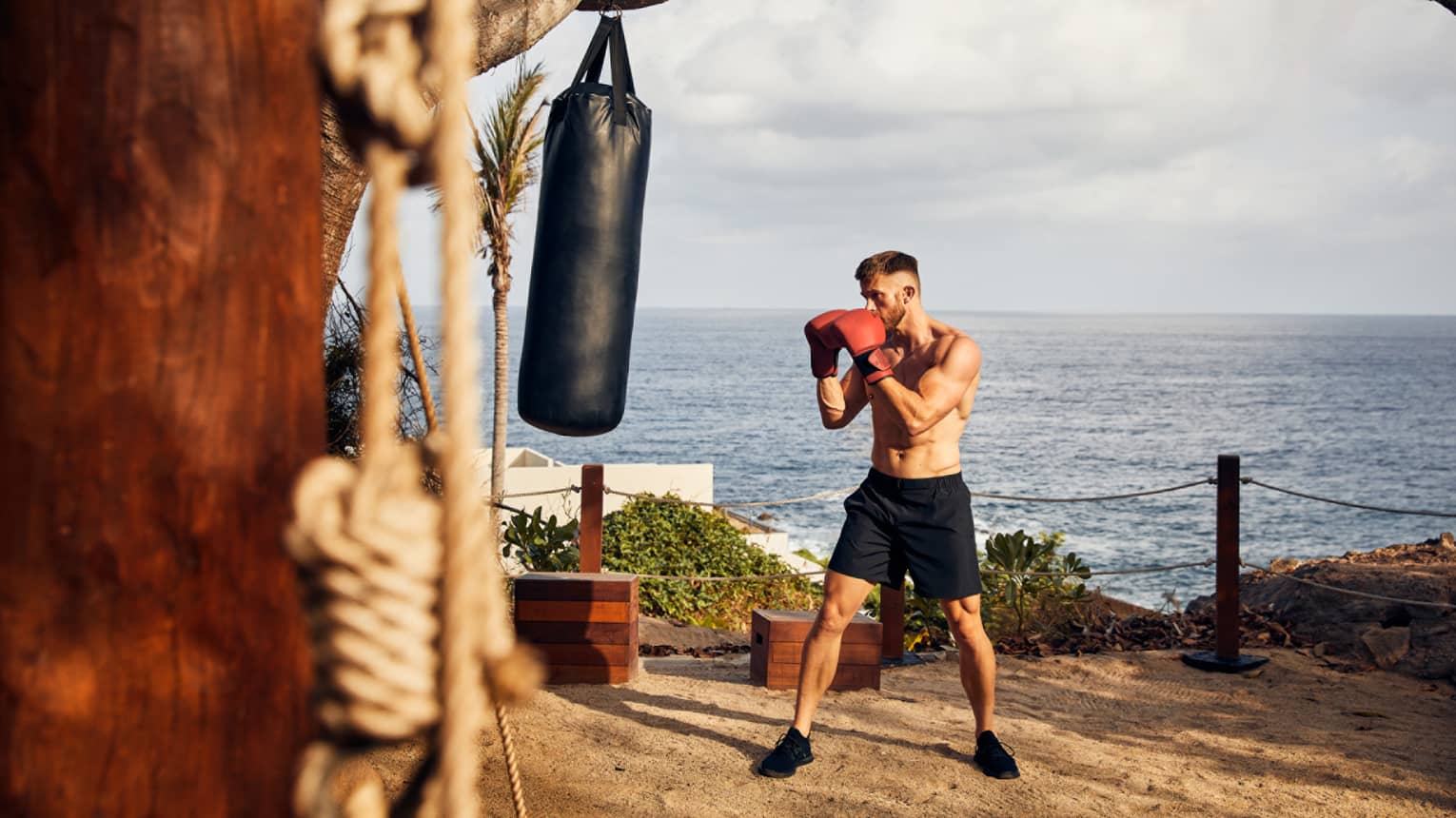 A guest engaged in a boxing session, perched above a cliff overlooking the Pacific Ocean