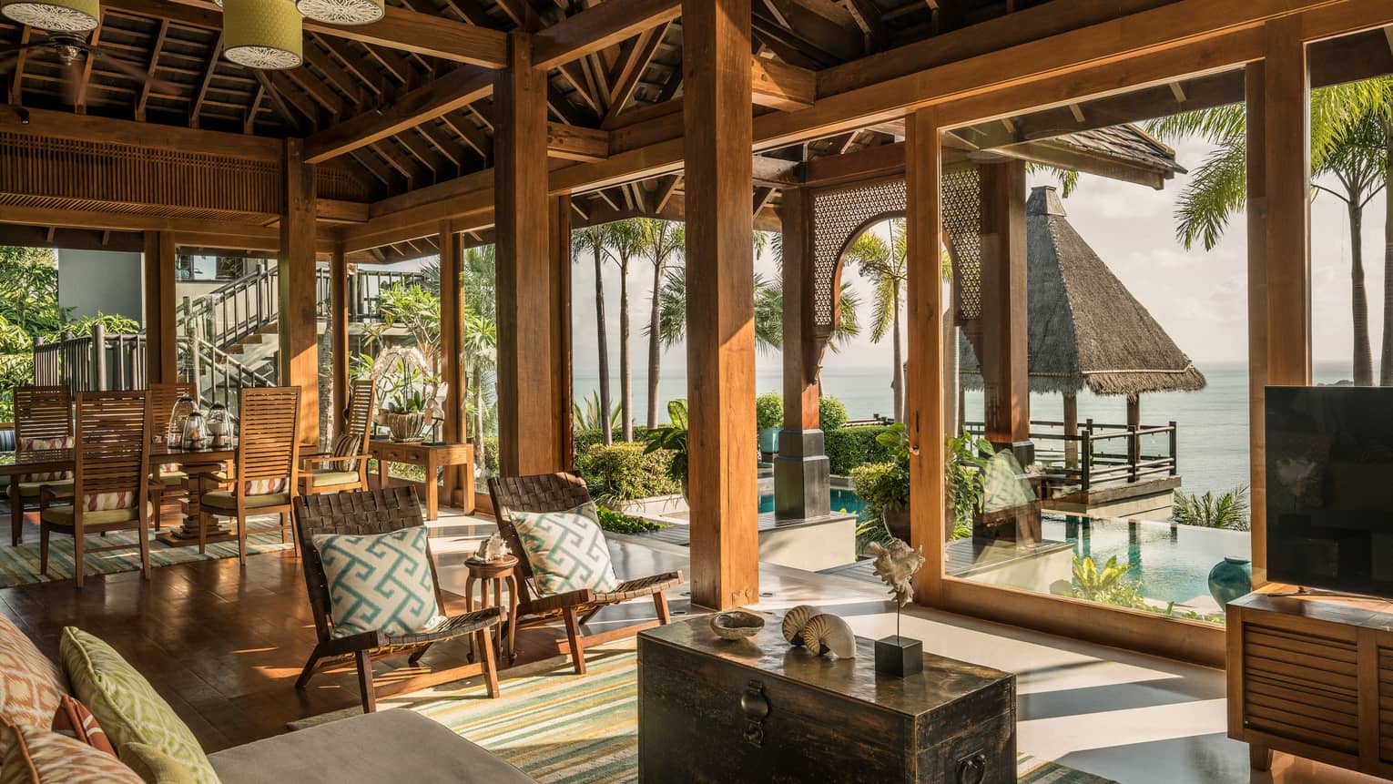 Bright, open air living and dining room, seats under rustic wood beam ceilings