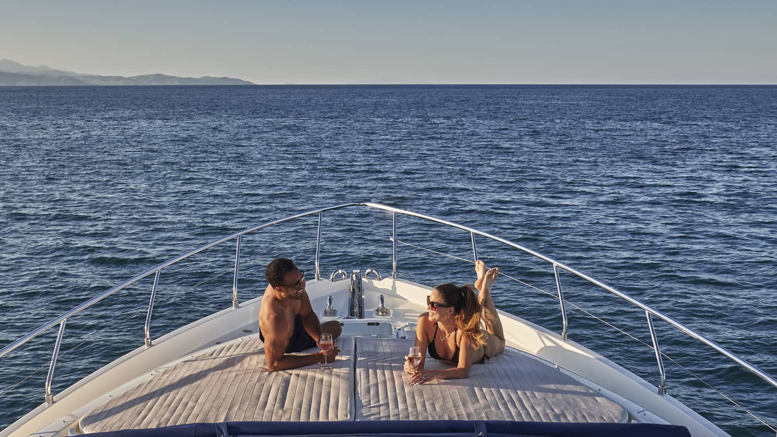 Man and woman lay on front of yacht