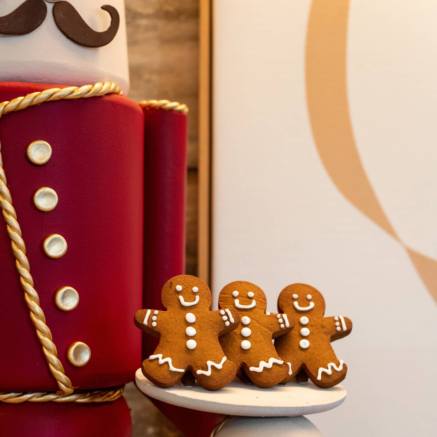 Gingerbread men cookies being held by a large nutcracker doll.