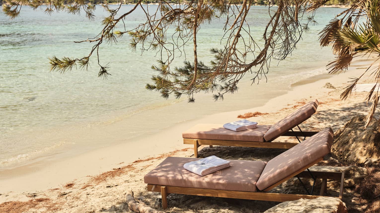 Two lounge chairs on a beach in tropical location