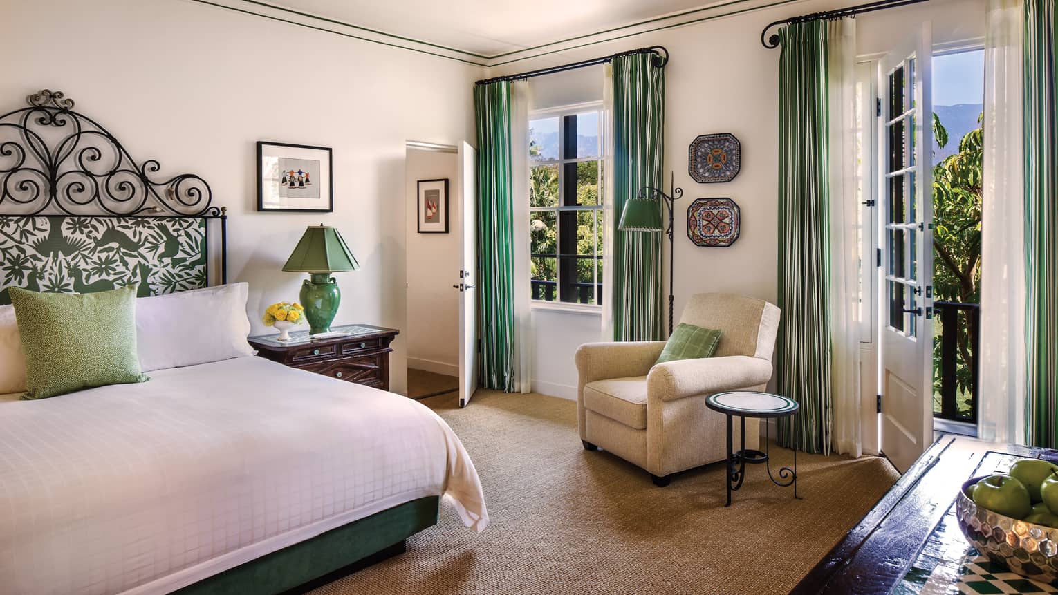 Garden Suite bed with iron and green-padded headboard, armchair between window, door
