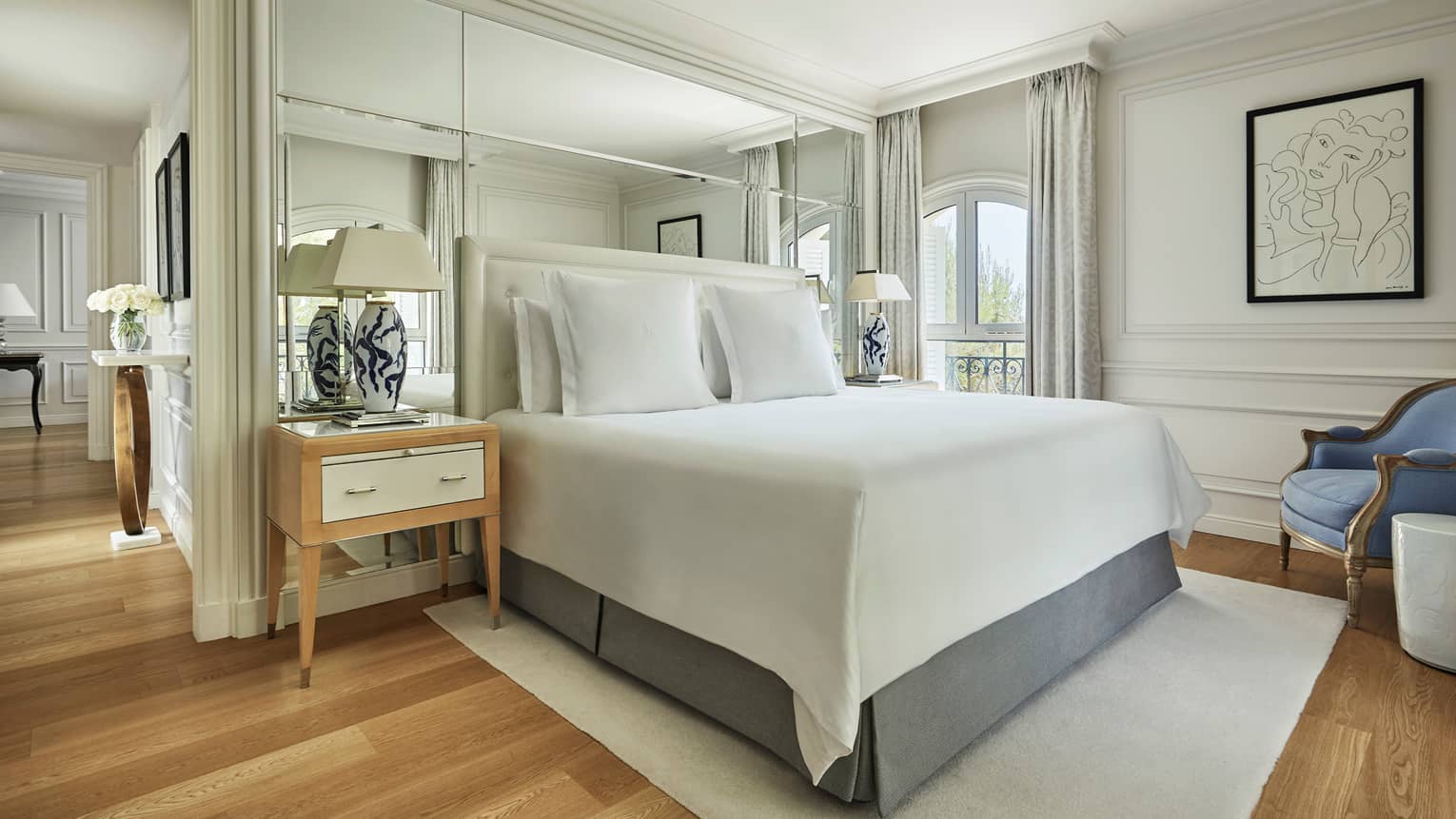 Four Seasons Pinewood Suite bed, nightstand with black-and-white lamps, wood floors