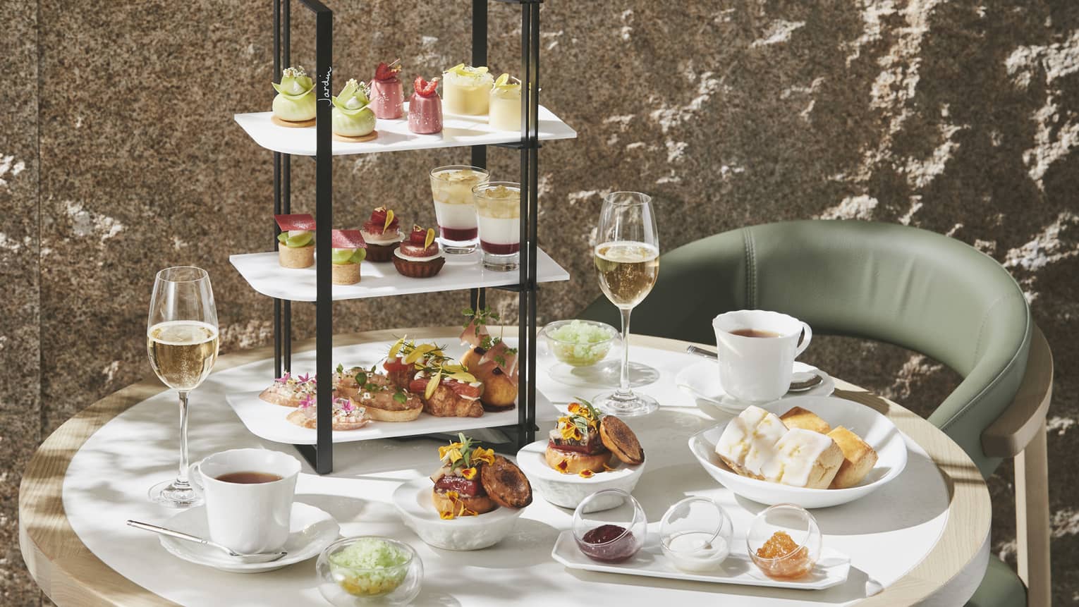 Afternoon Tea set up with three-tiered display of sweet and savoury foods, two glasses of champagne and two glasses of tea