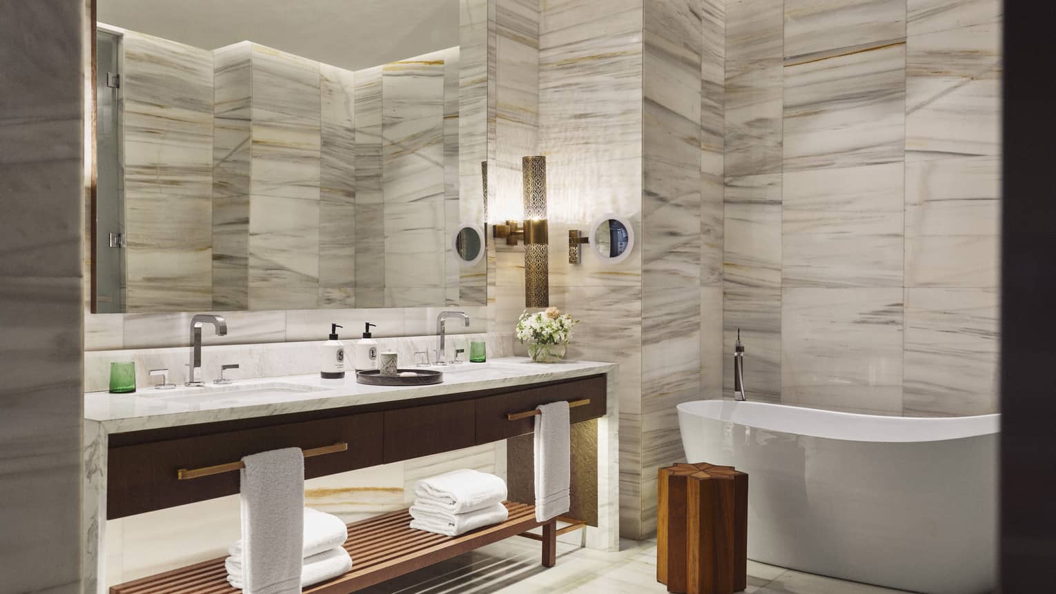 Hotel suite bathroom with marble walls and freestanding tub