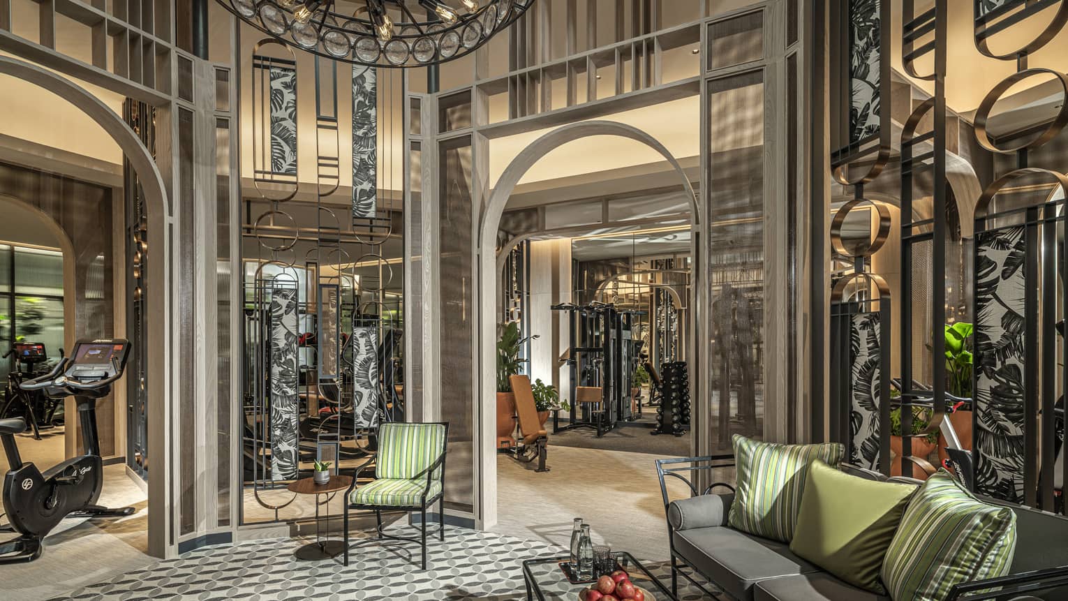 Fitness Centre lobby with high ceilings, round wrought-iron chandelier, sofa with green accent pillows