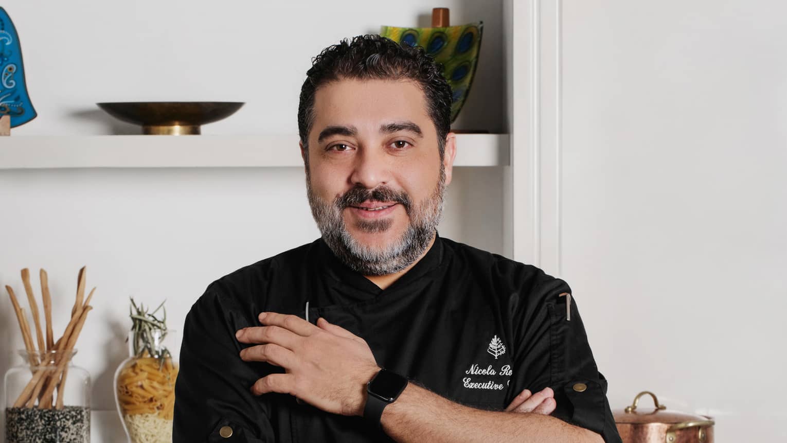 Executive Chef Nicola Rossi in black chef's coat, standing in kitchen with arms crossed