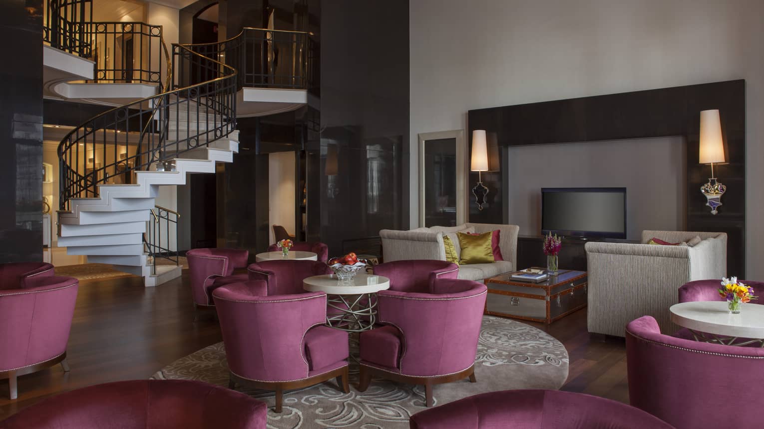 A seating area with purple chairs at the bottom of a spiral staircase.