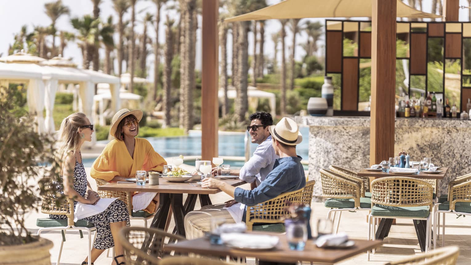 Friends enjoying lunch outdoors by the pool in luxury hotel
