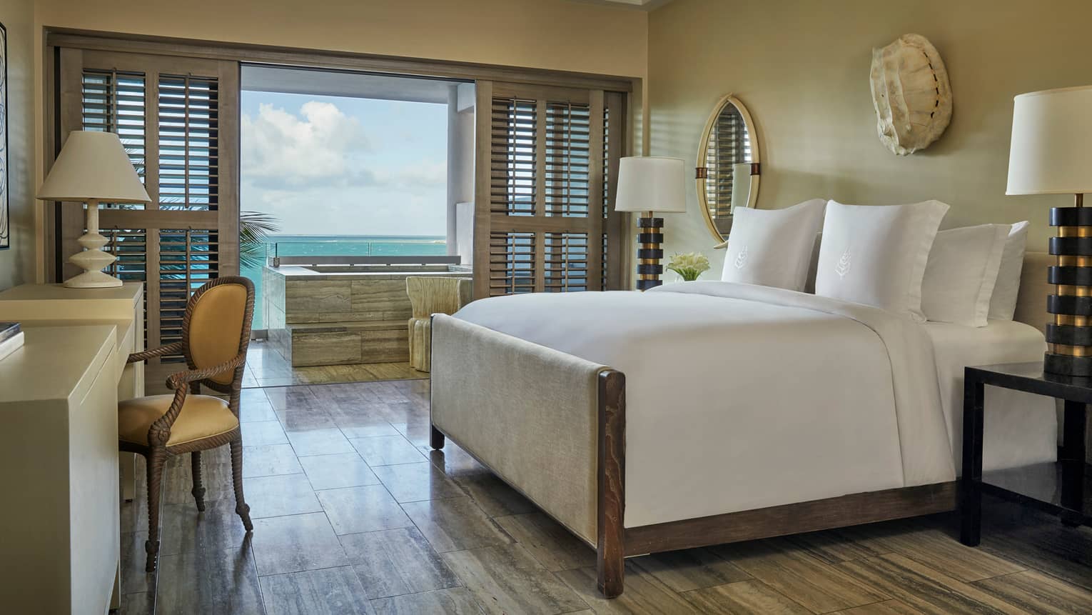 Ocean-View Studio Room bed, desk, bedside lamps, white wall sculpture, patio doors with wood shutters