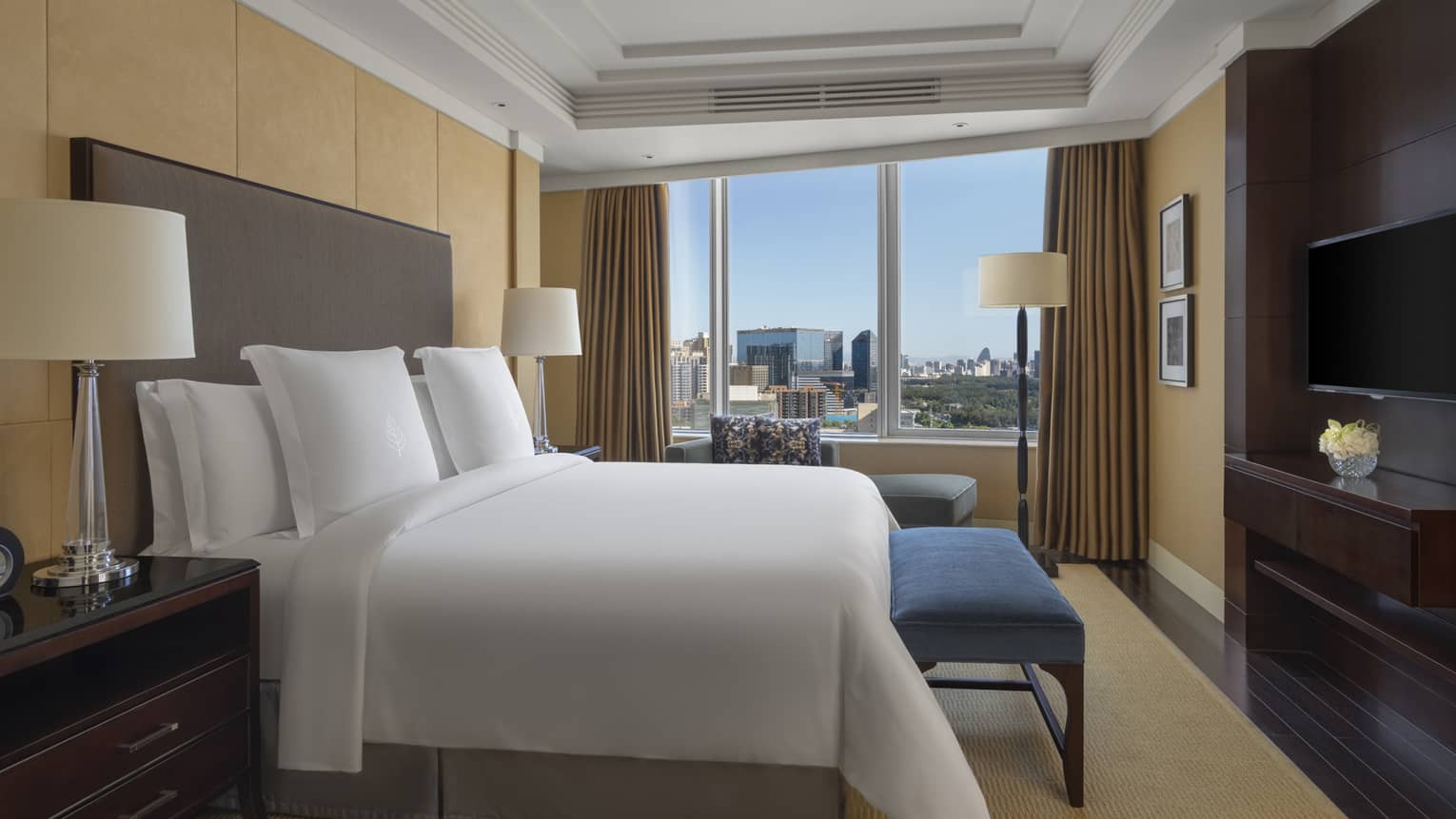 Hotel room with king bed, blue bench, windows and curtains