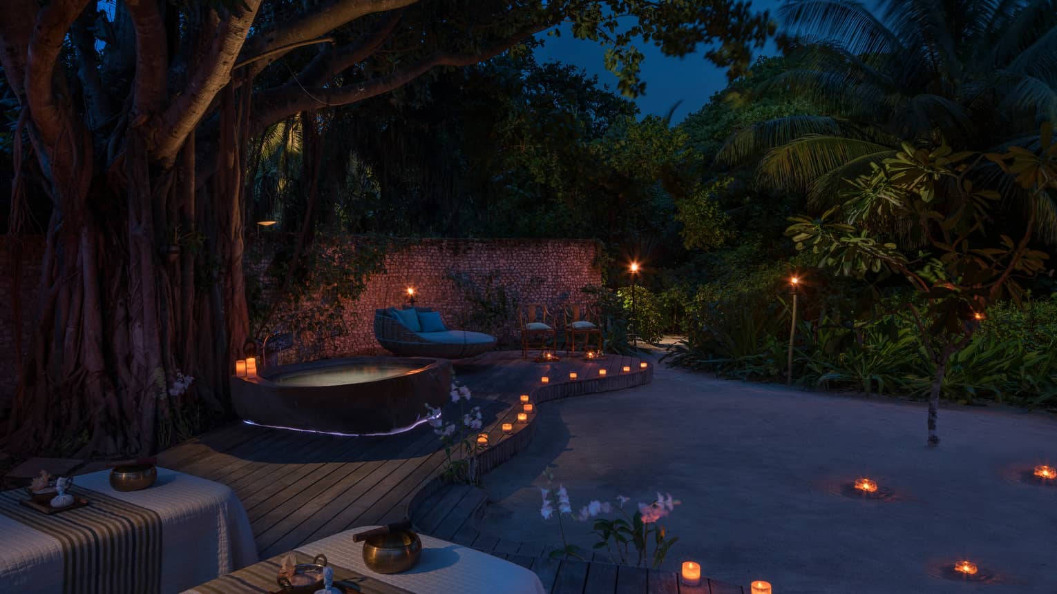 Candles along sand beach, spa patio, hot tub at night
