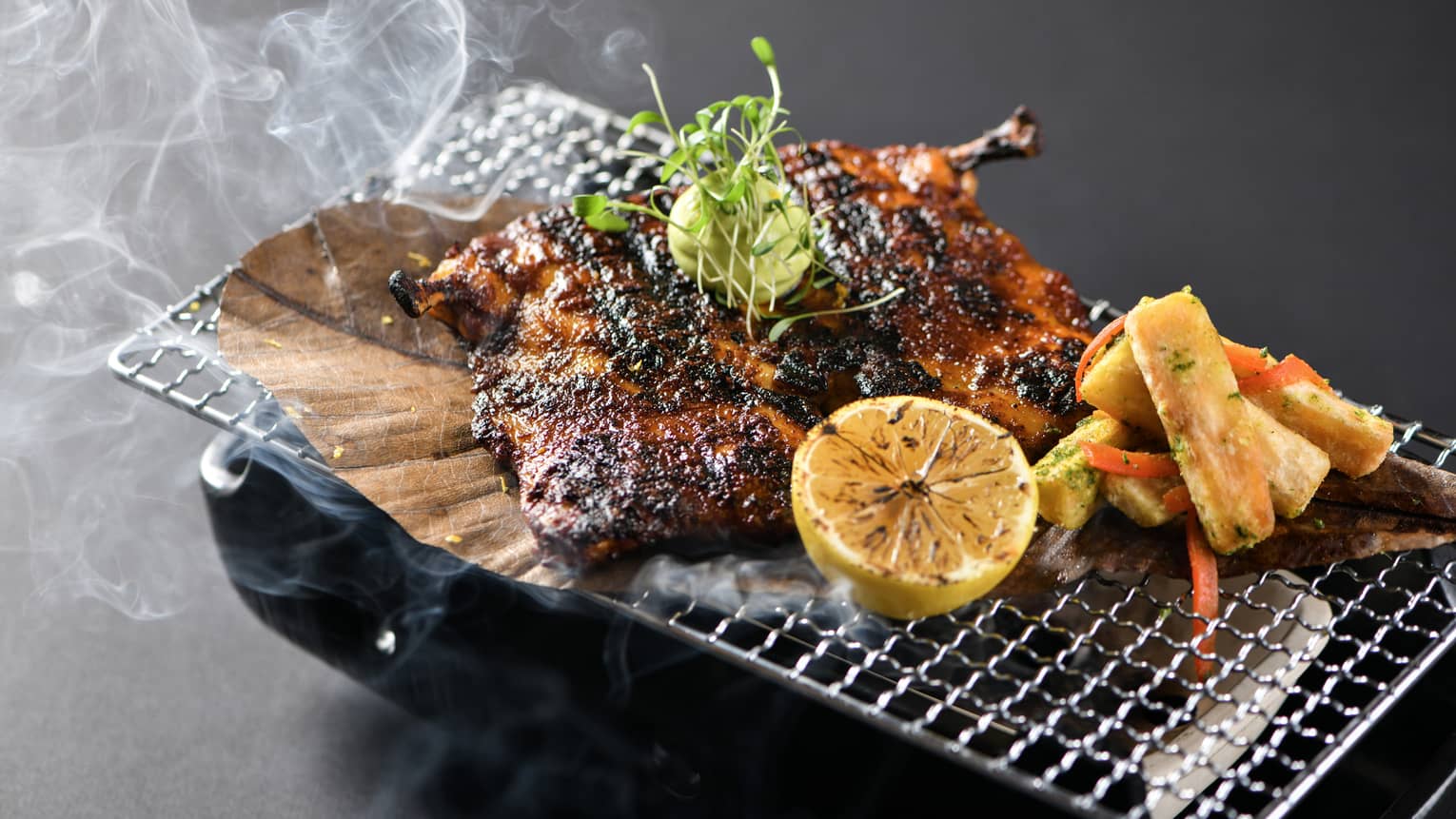 Grilled meat and vegetables served on a wire tray over a platter