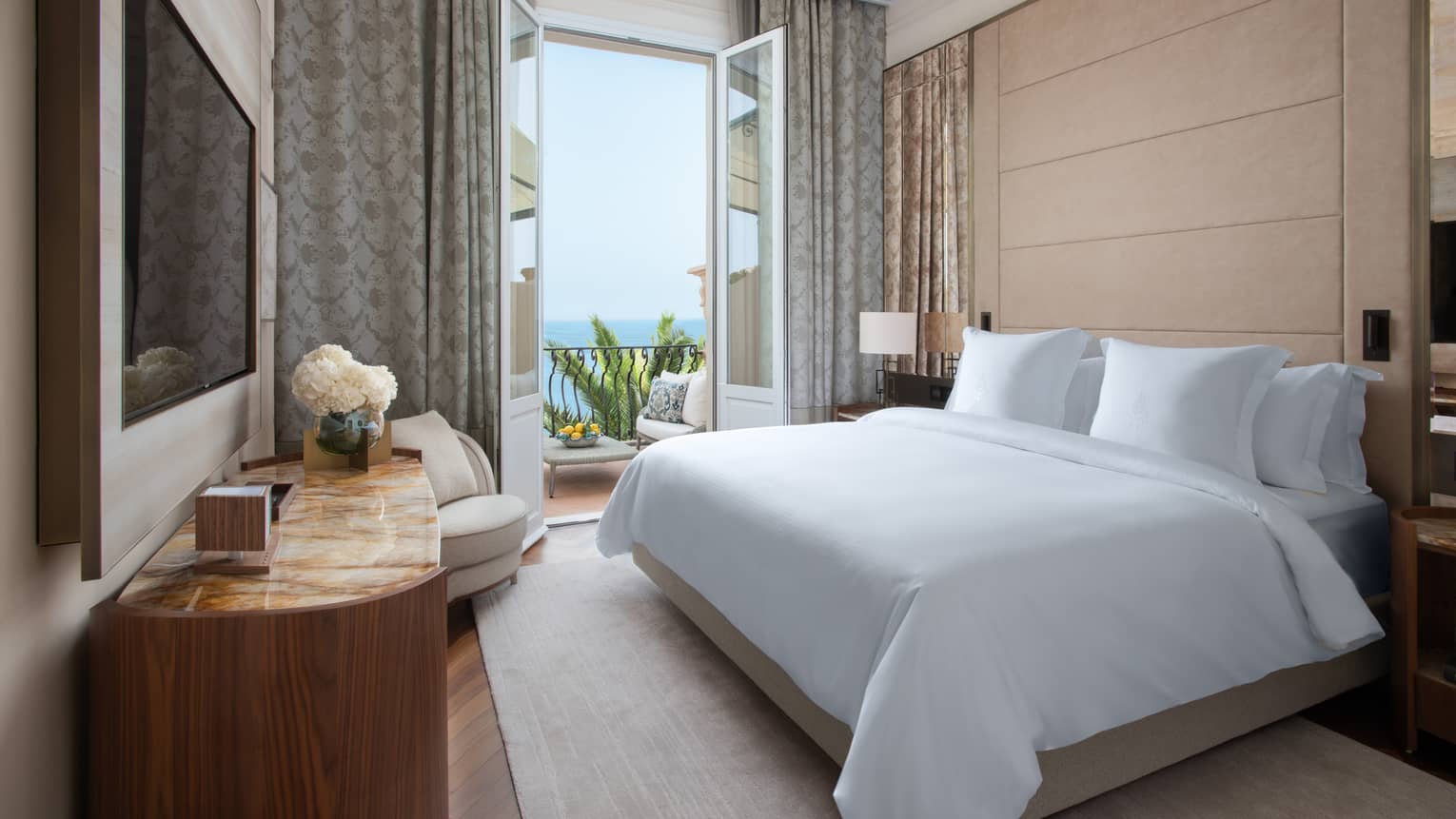 Royal Suite with king bed, white linens, flat screen TV, French doors leading to balcony with view of the Mediterranean Sea