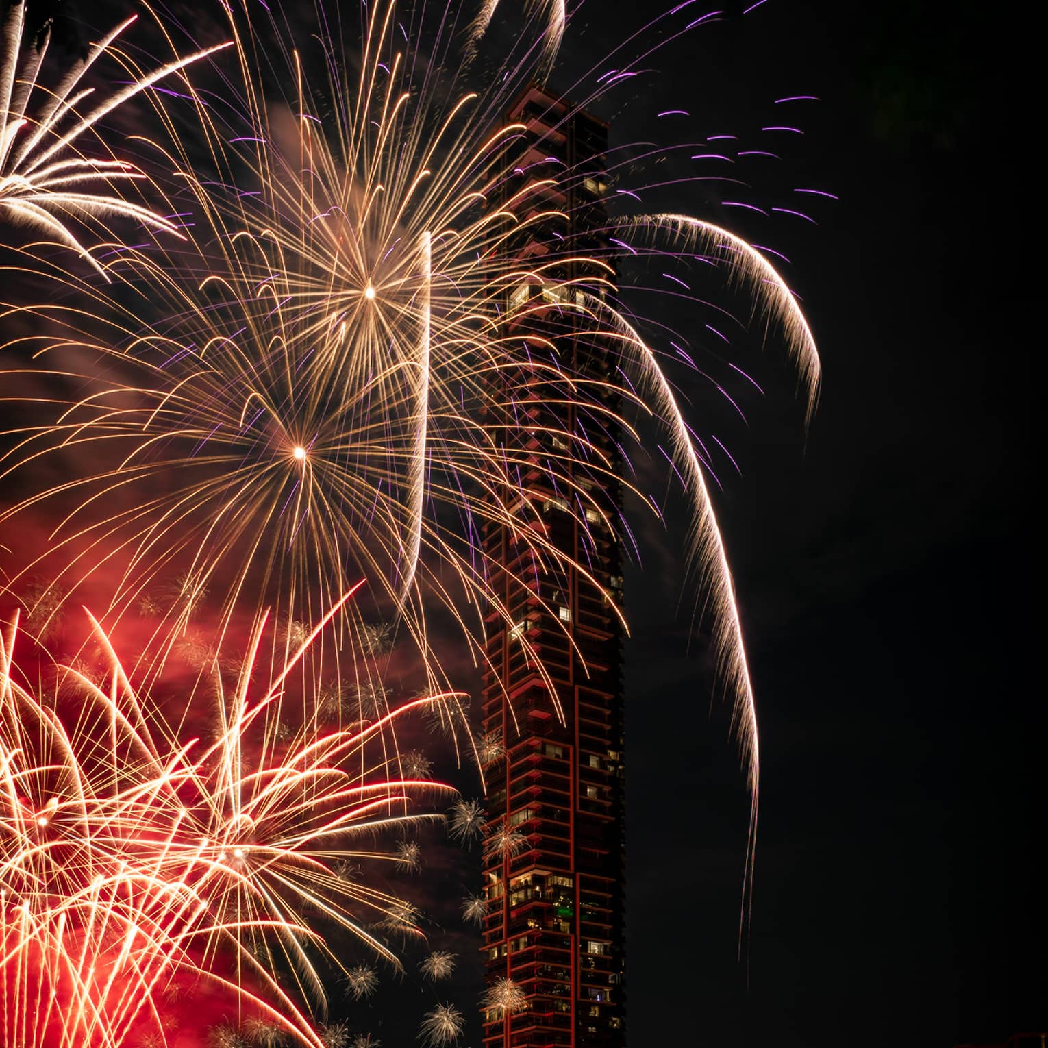 Colourful fireworks are set off at night by the river