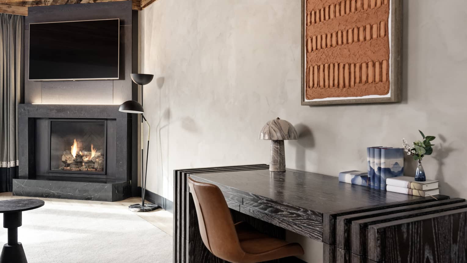 Desk in a hotel suite living area, with fireplace in the background