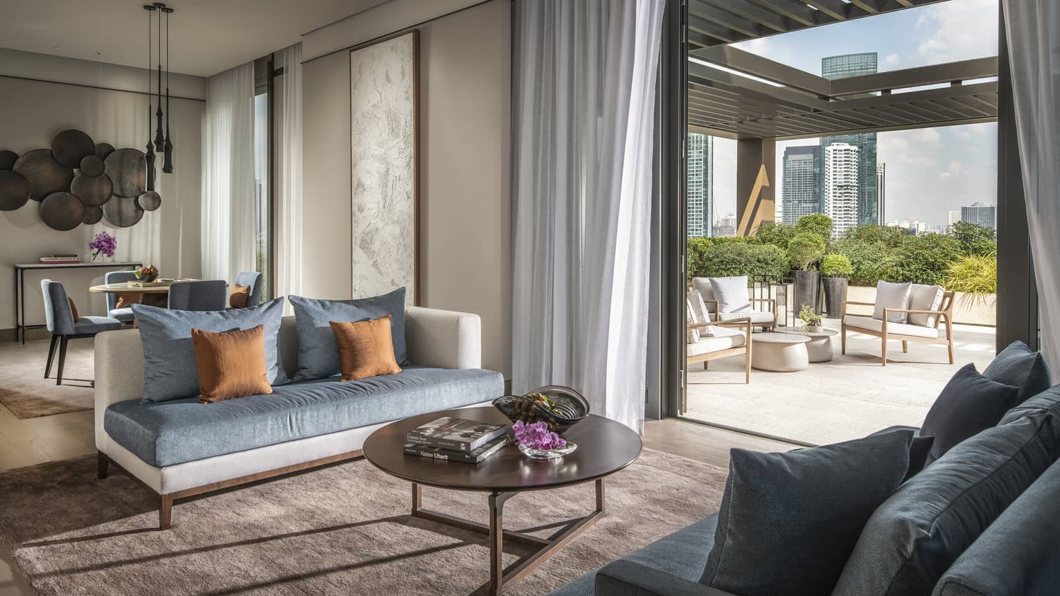 Hotel suite's living room opening up to a terrace with outdoor seating
