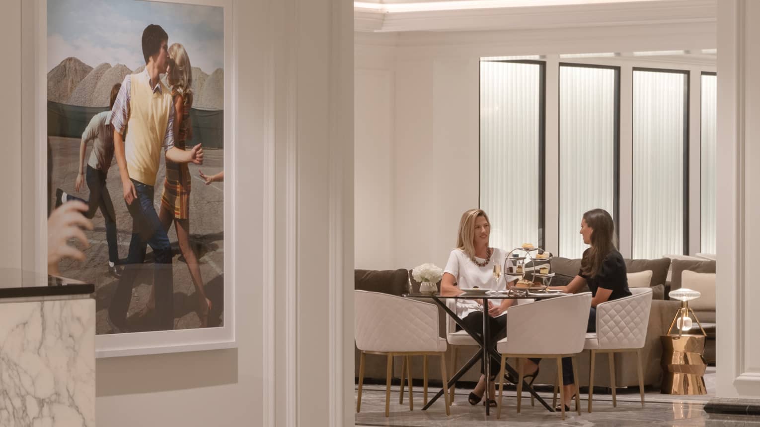 Two women sitting at a round table having a conversation.