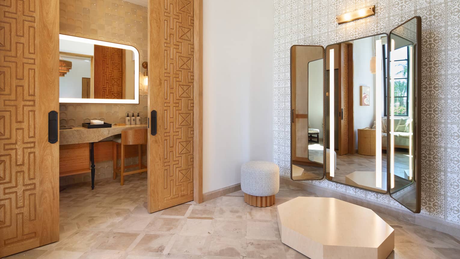 An indoor space with warm neutral decor, soft yet bright lighting, and a small dais in front of three large wall mirrors