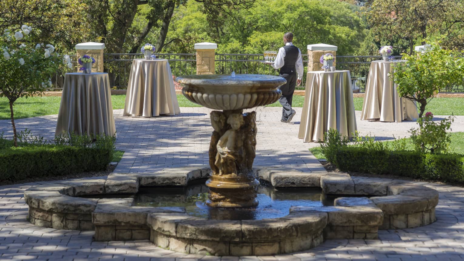 Fountain in garden event space dotted with small cocktail tables