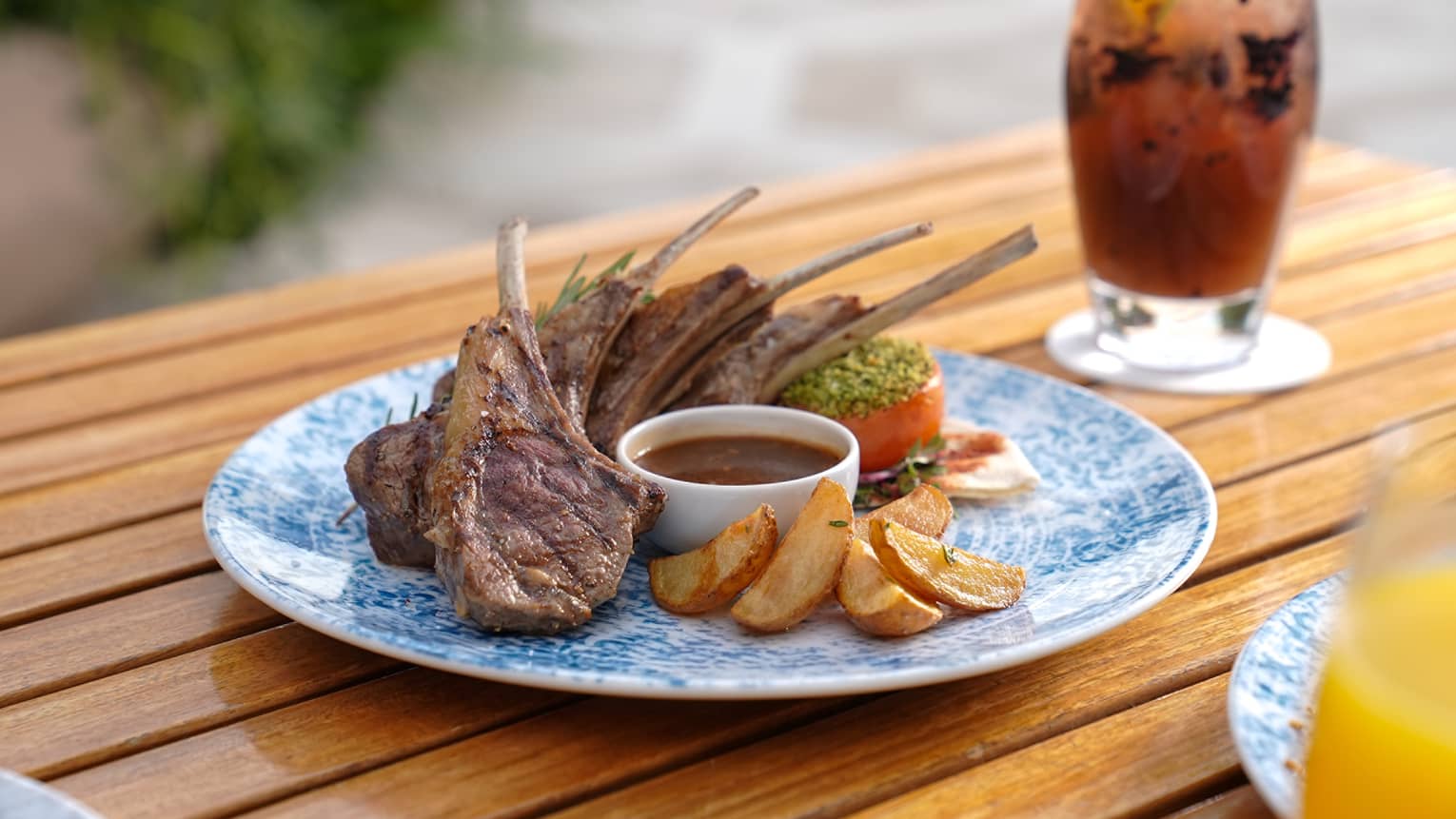 Lamb chops on a plate next to a cocktail.