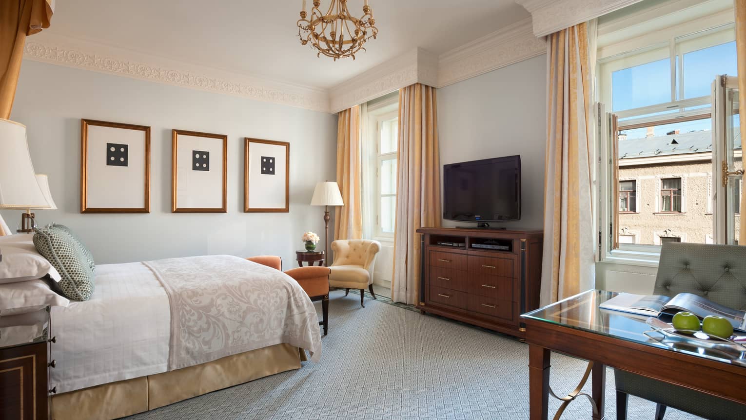 Premium Room single bed under three gold-framed prints, facing two bright windows, desk