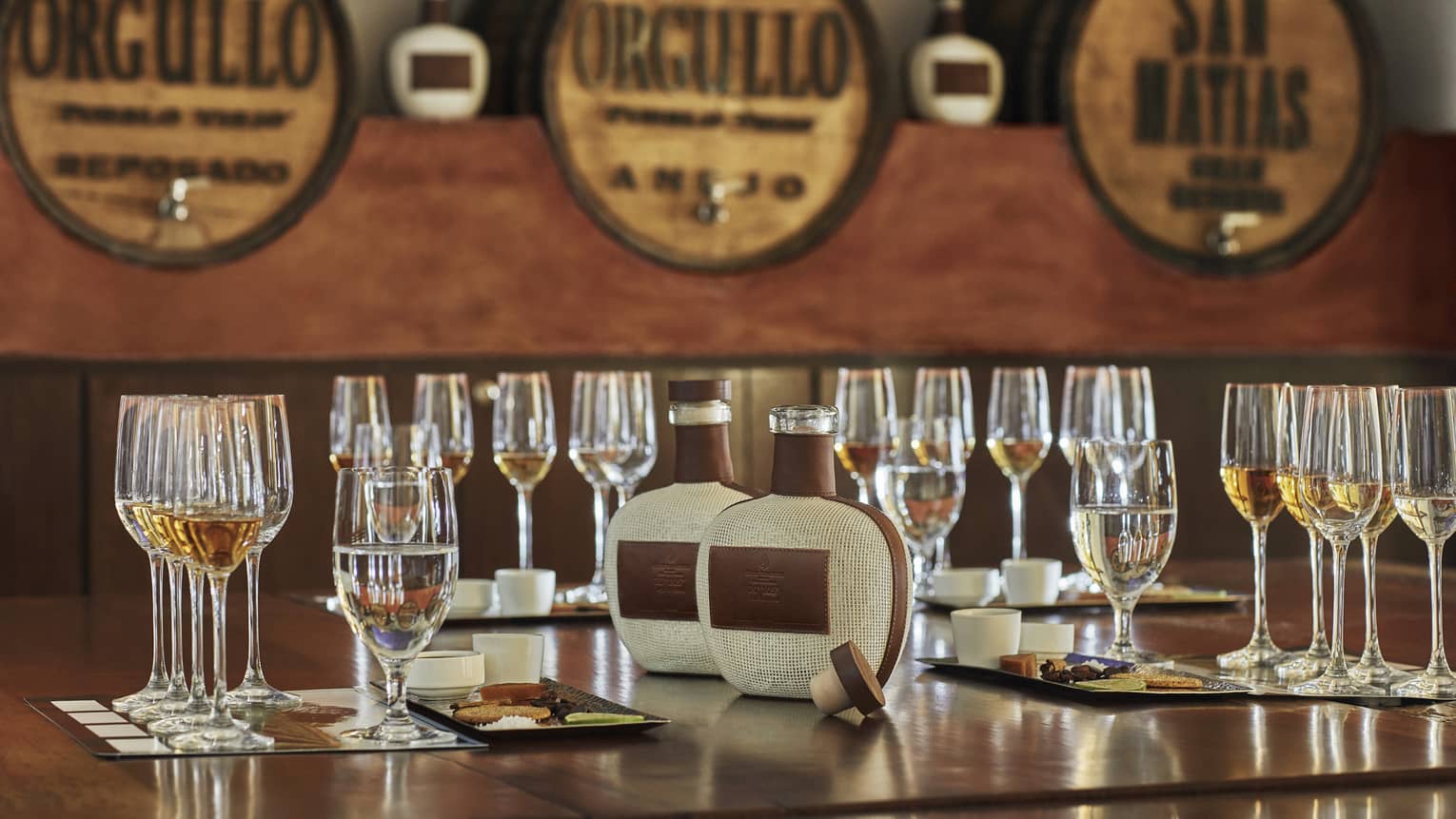 Tequila tasting, rows of wine glasses and cheese plates on table near tequila taps