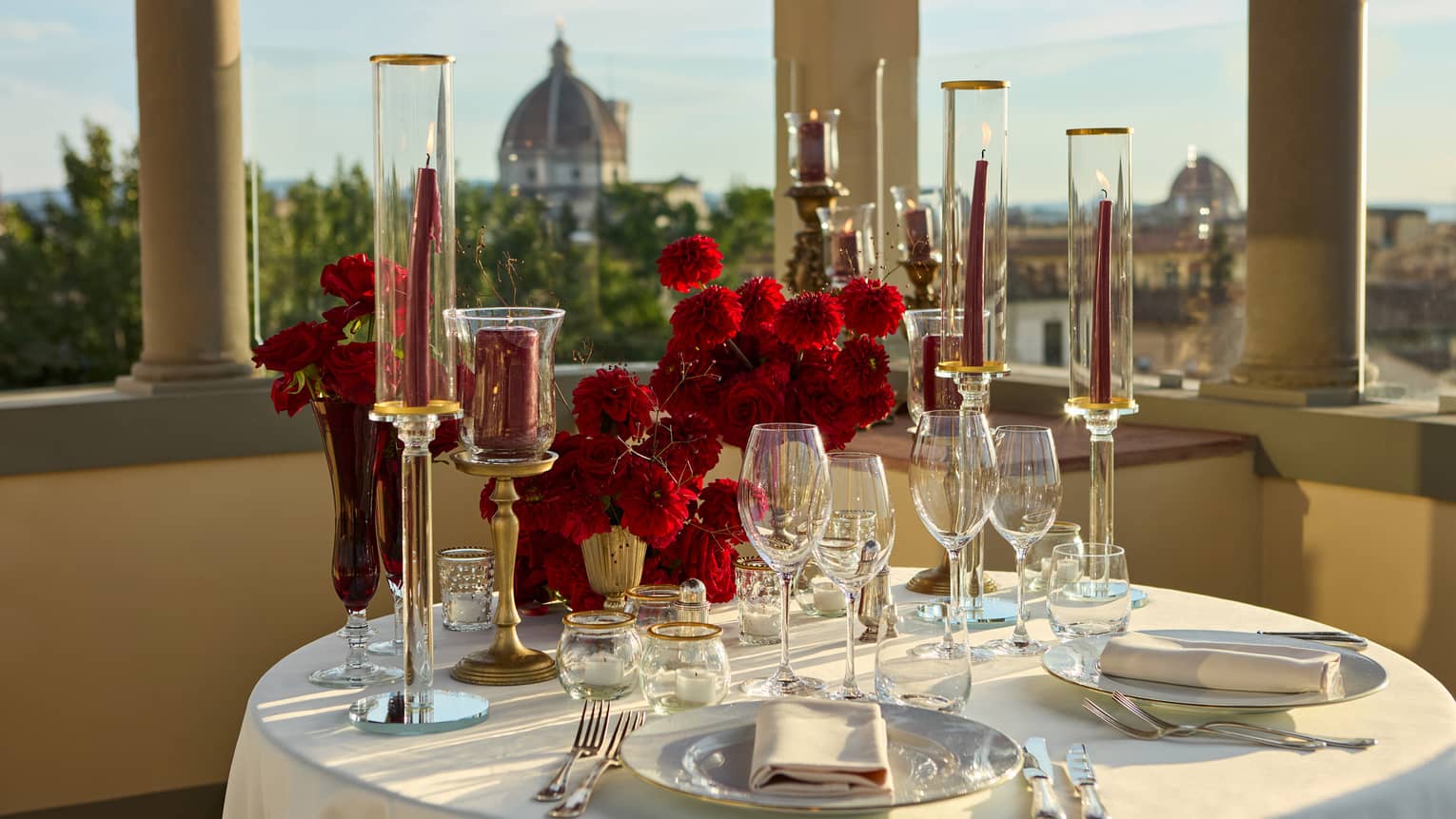 Terrace with elegant, romantic table set for two with crystal glassware and candlesticks looking out to the Duomo