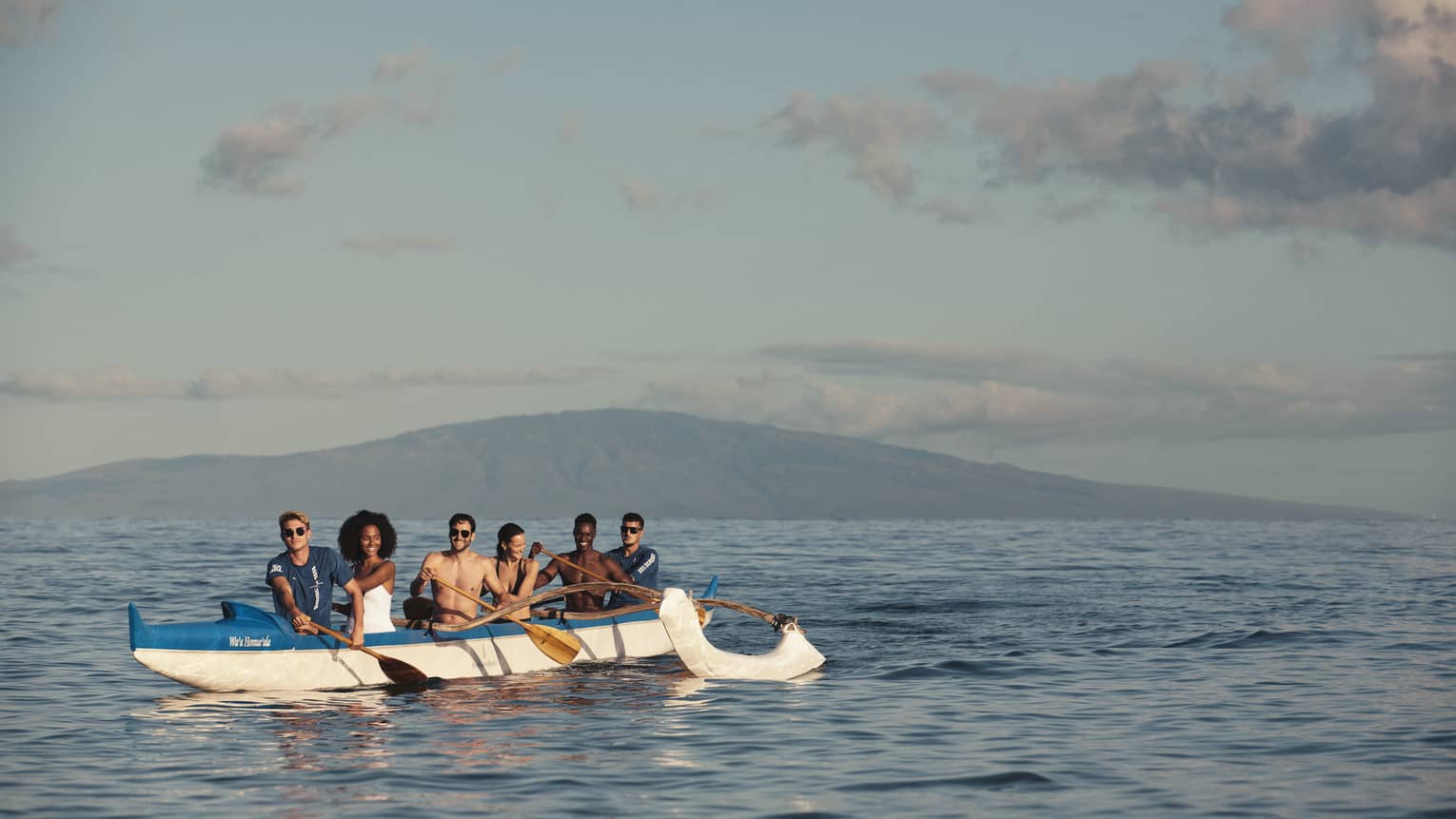 A group of 6 people on an outrigger canoe in ocean in Maui