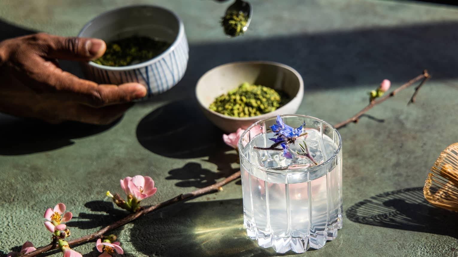 A clear cocktail with lavender as a garnish.