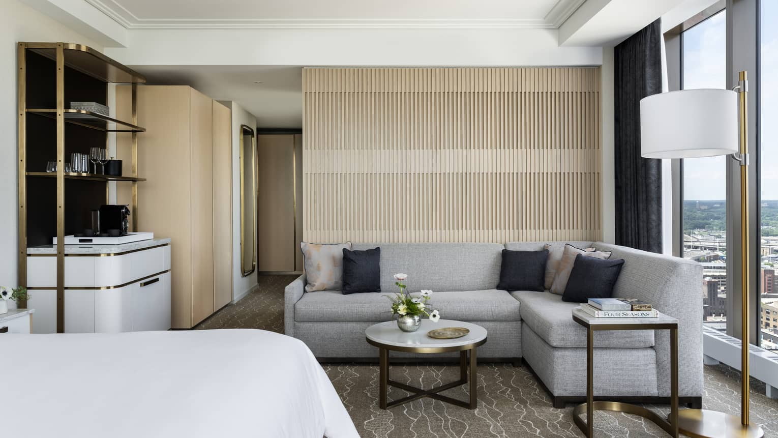 Hotel room with sitting area, complete with a grey sofa and marble coffee table