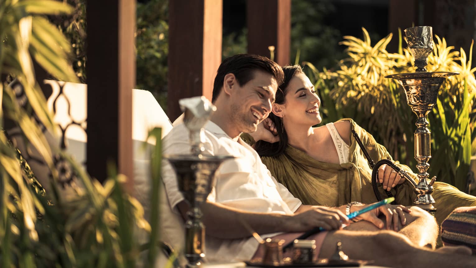 A couple sits together on lounge chairs outside at Four Seasons Hotel Kuala Lumpur