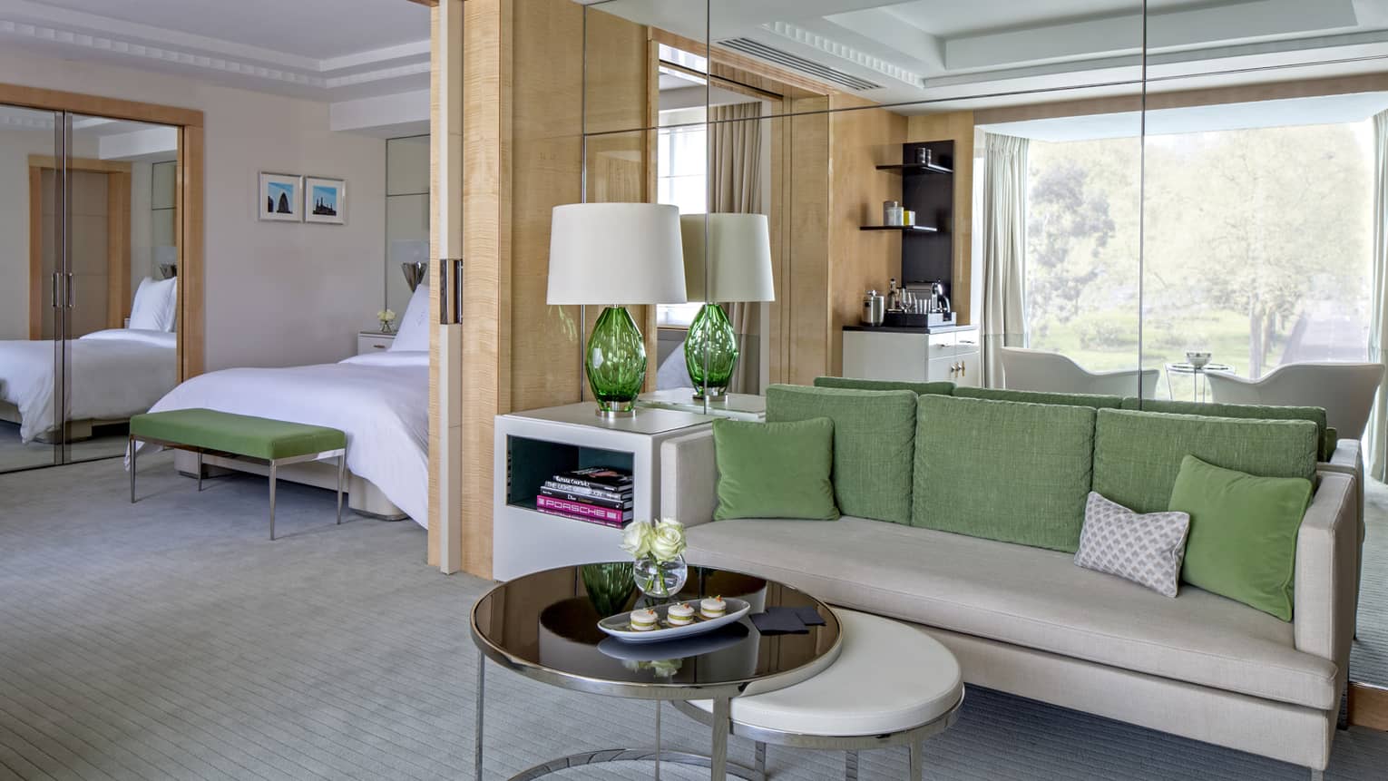 Mayfair Suite grey sofa with green pillows, round tables, alcove with bed, mirror