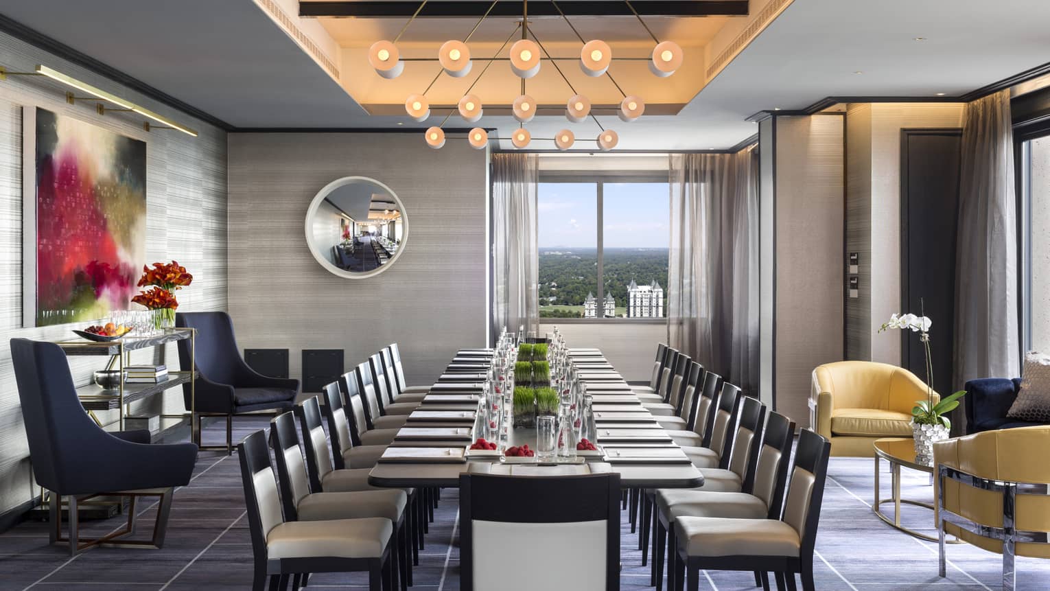 A modern light fixture hangs over a long, set table