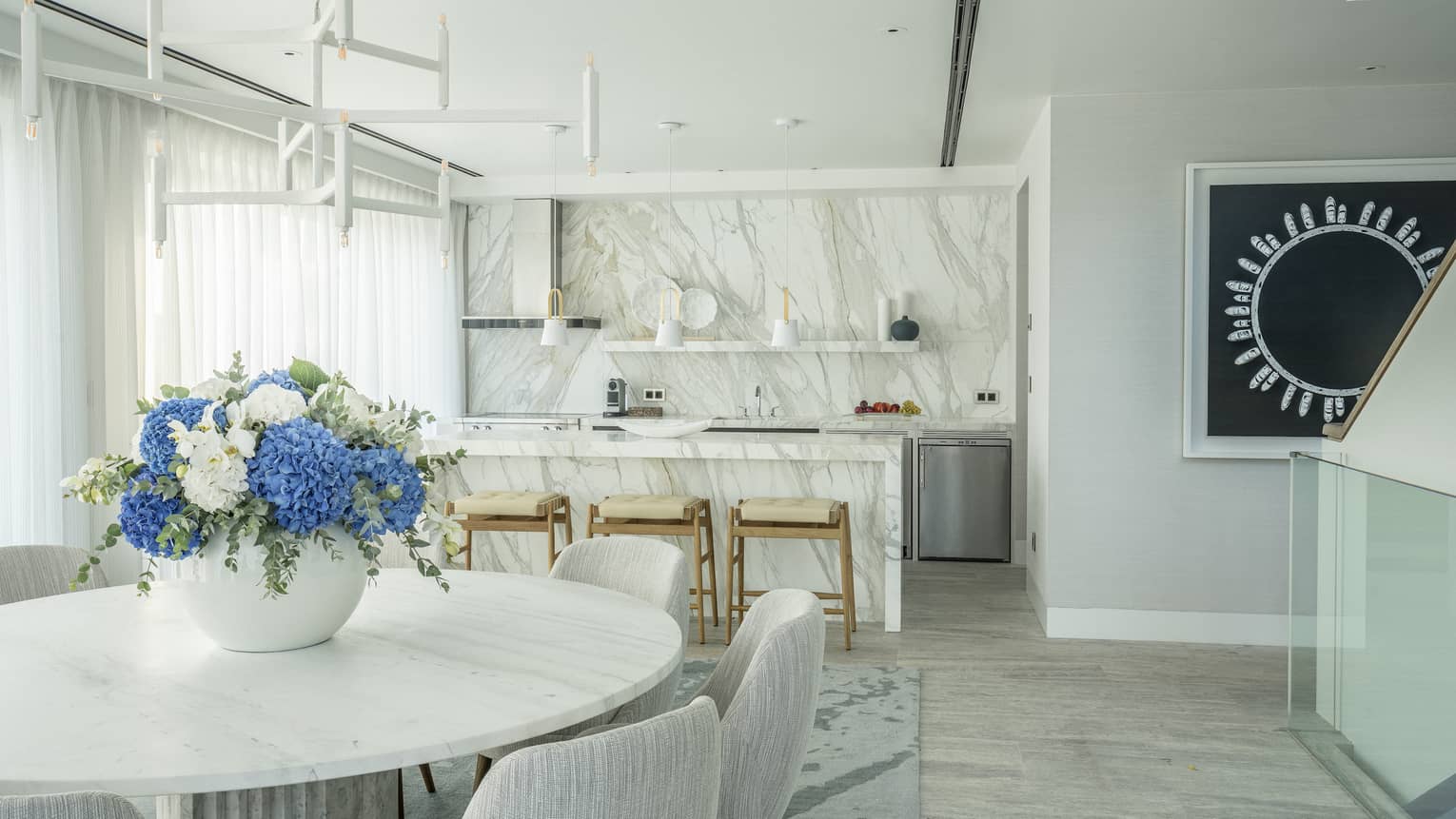 Arion Riviera Suite dining area with round table, white bucket chairs, marbled kitchen island with stools