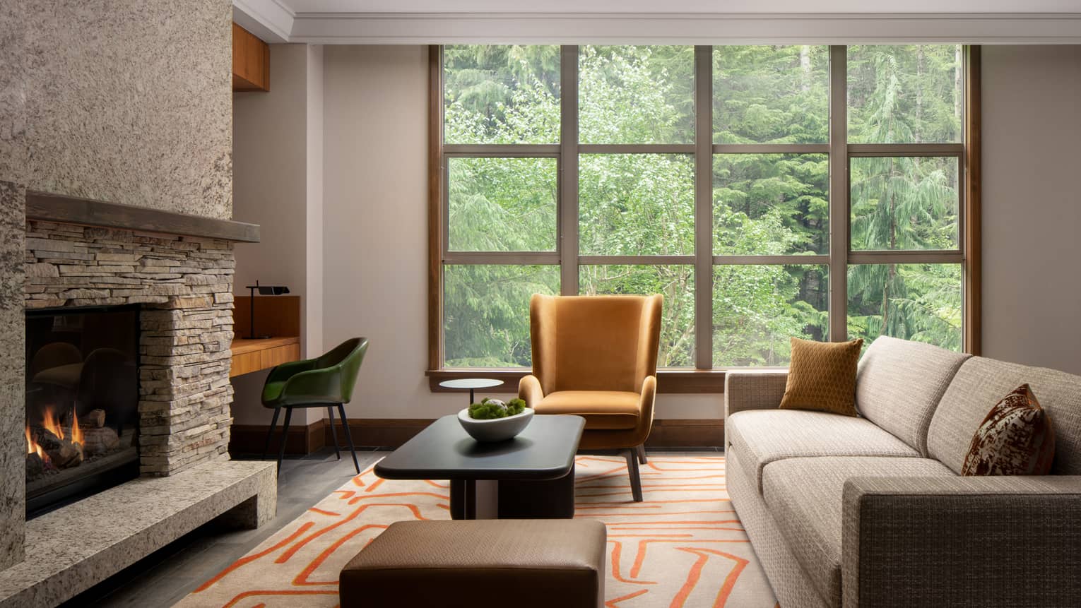 Elegant living area of a luxury vacation rental at Four Seasons Whistler. The room features a large window with a view of dense green trees, a stone fireplace, and modern furnishings. A beige sofa with decorative pillows, a mustard yellow armchair, a dark wood coffee table, and a geometric patterned rug add warmth and style to the space.,Elegant living area of a luxury vacation rental at Four Seasons Whistler. The room features a large window with a view of dense green trees, a stone fireplace, and modern furnishings. A beige sofa with decorative pillows, a mustard yellow armchair, a dark wood coffee table, and a geometric patterned rug add warmth and style to the space.