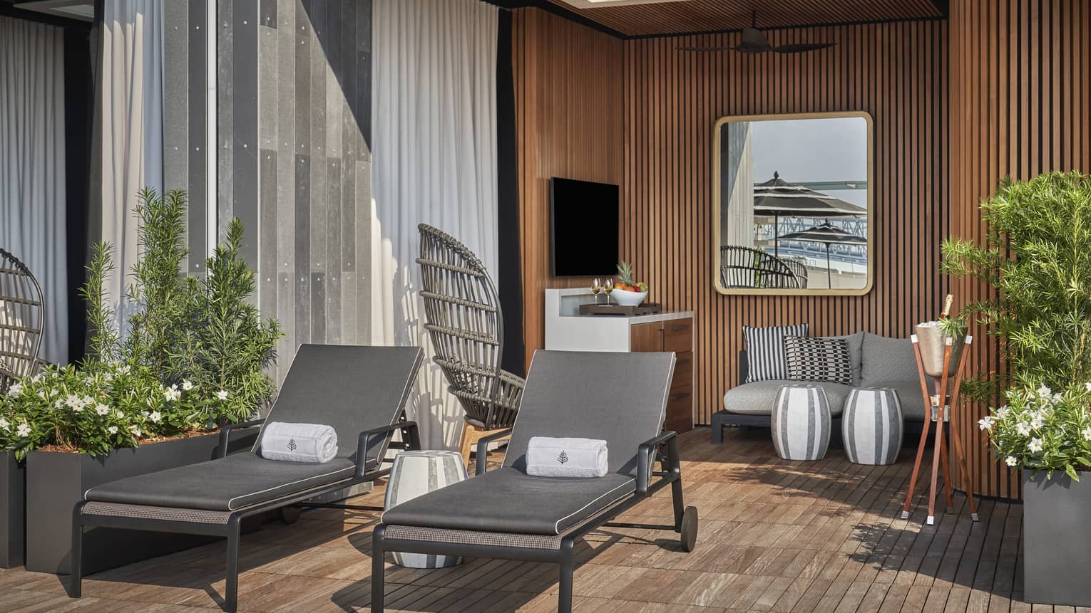 A cabana with two lounge chairs a sofa and plants.