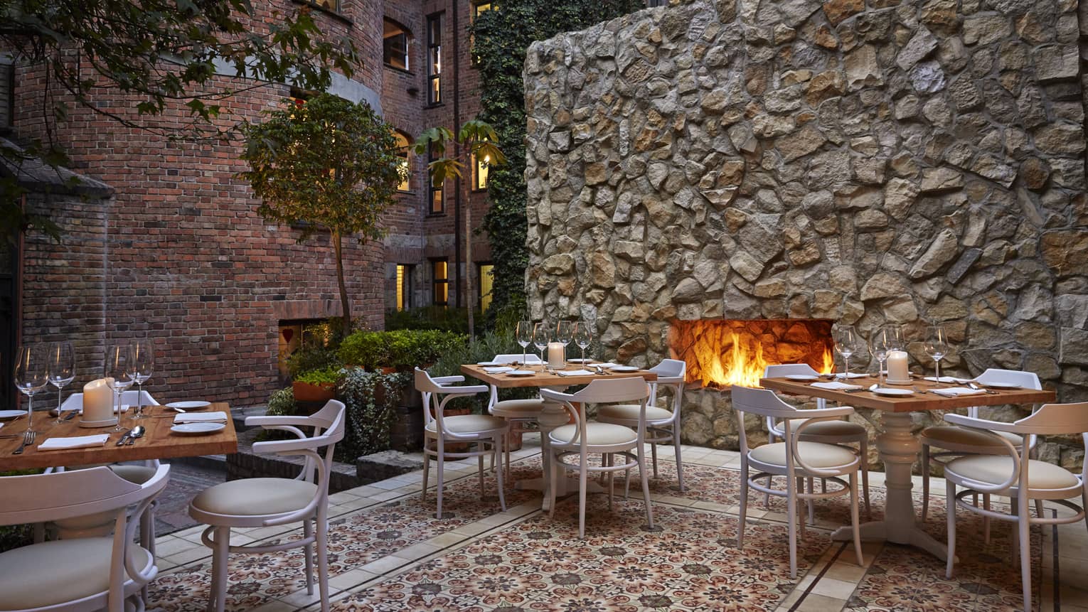 An outdoor patio with a fireplace, and several tables and chairs set up around.