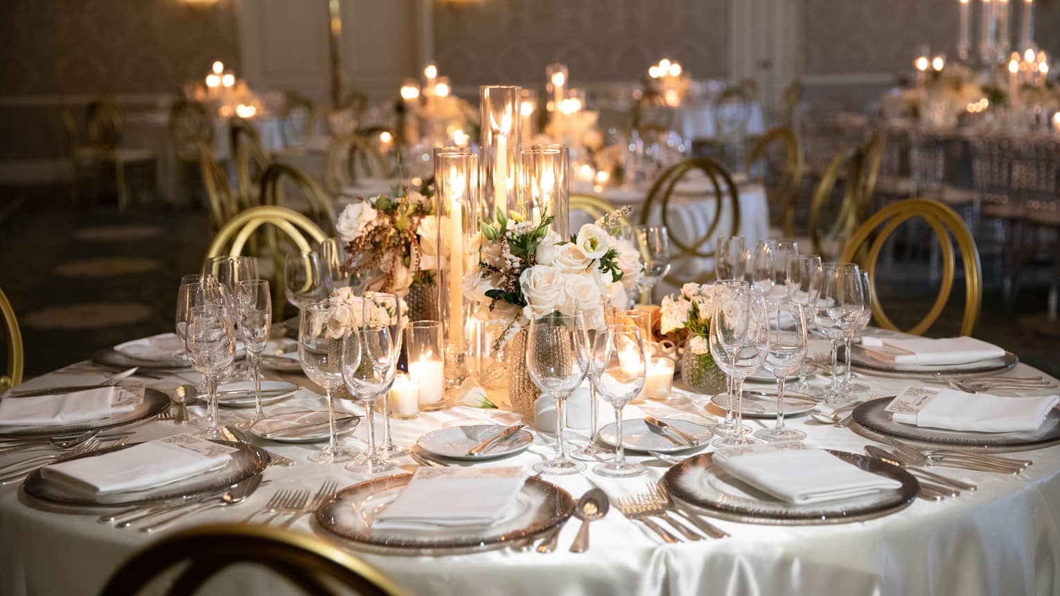 Round wedding banquet dining table with white flowers, glowing candles